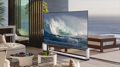 LG OLED Z2 is in a minimalist white room in front of a window that looks onto a forest of trees