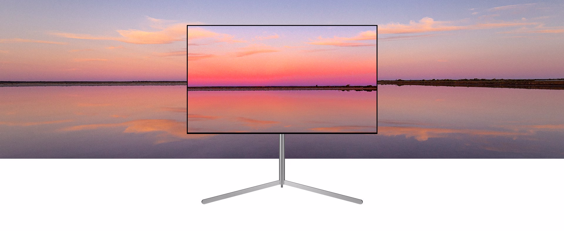 An LG OLED television on a Gallery Stand depicts a blue and pink sunset which blends into the background